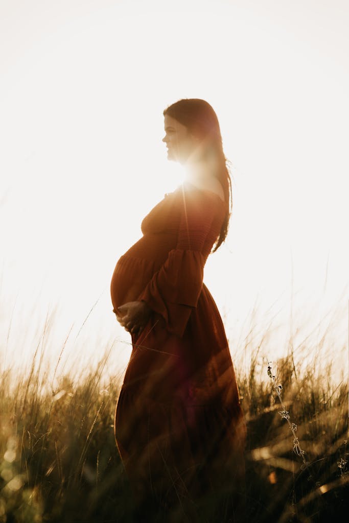 Discovering Moxibustion: An Ancient Healing Technique in Acupuncture 10 Serene pregnant woman in a sunlit field, embracing nature and motherhood.