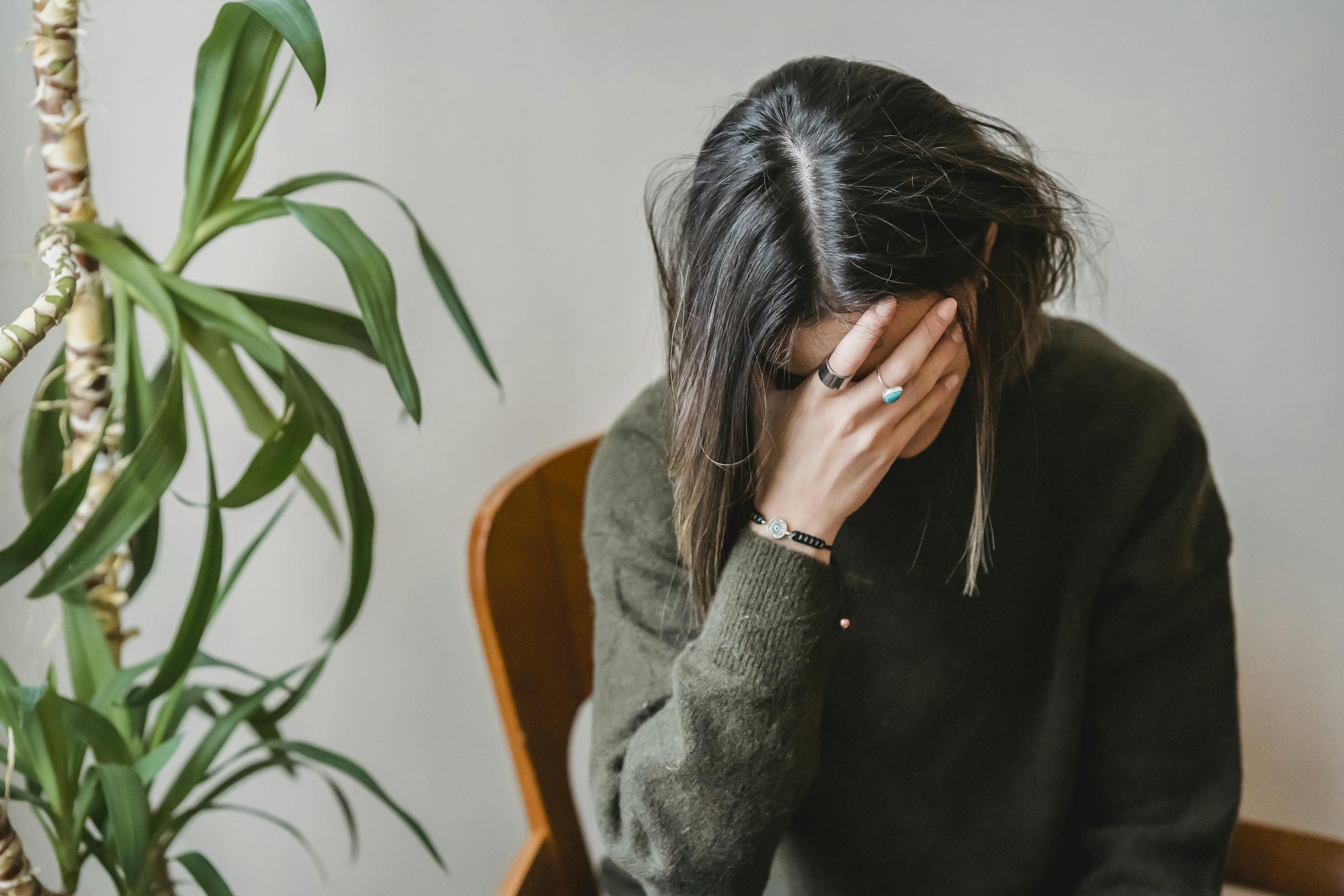 Finding Balance: How Acupuncture and Chinese Herbal Medicine Can Help with Anxiety and Depression 8 Unrecognizable young upset female millennial with dark hair in stylish sweater covering face with hand while siting on chair at home