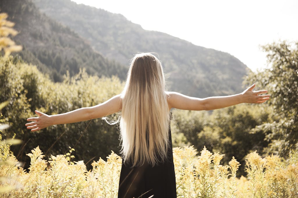 New Year, New You: Setting Intentions for Health and Harmony in 2025 10 Young woman with arms open, enjoying freedom in a mountainous landscape.